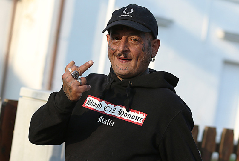 Neonazi aus Nordrhein-Westfalen mit dem Shirt von » [Blood & Honour](/die-symbolwelt/gruppen-organisationen-und-netzwerke/blood-honour-b-h) - [Combat 18](/die-symbolwelt/gruppen-organisationen-und-netzwerke/combat-18-c18) Italien« und Fred Perry-Kappe im Jahr 2018.