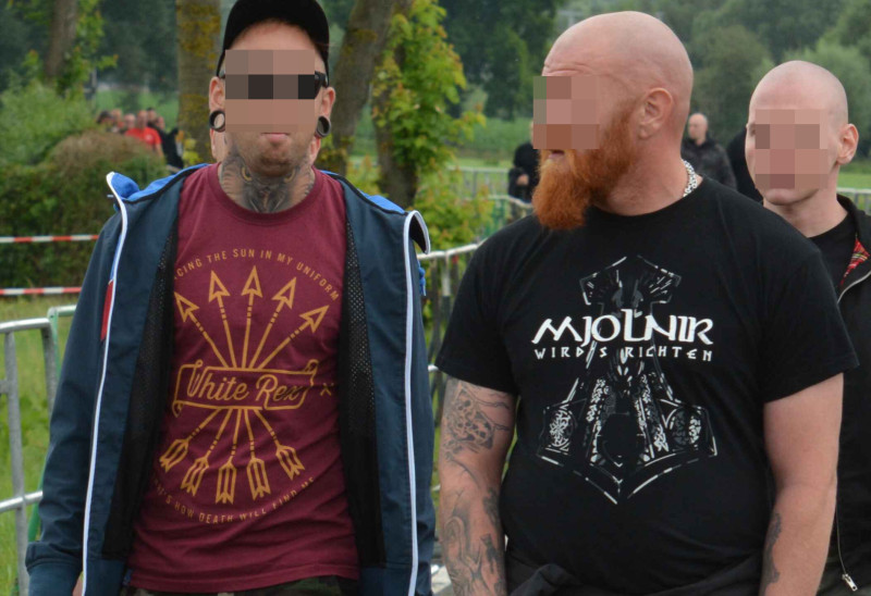 Teilnehmende eines Neonazikonzerts in Thüringen 2017: Links die neonazistische Modemarke [White Rex](/die-symbolwelt/bekleidung-und-marken/white-rex), rechts ein Thorshammer-Motiv und die Aufschrift "Mjölnir wirds richten".