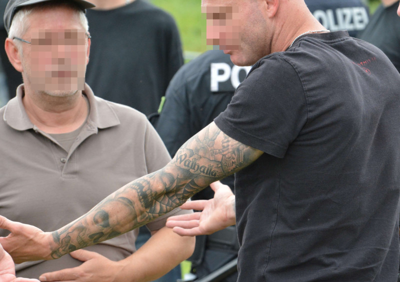 Polizisten am Eingang eines Neonazi-Konzertes in Thüringen im Sommer 2017 entscheiden, welche Tätowierungen offen gezeigt werden dürfen. Der Walhalla-Schriftzug dieses Neonazis blieb freilich unbeanstandet.